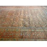 A LARGE RED GROUND PATTERNED WOOLLEN CARPET with multiple border, 453 x 340 cms (quite worn with