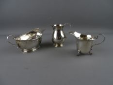 A SILVER SAUCE BOAT, a silver cream jug on hoof feet and one other on a circular base, Birmingham