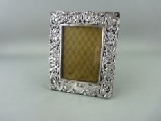 A SILVER EASEL PORTRAIT FRAME for a picture 9 x 13 cms, the wide frame of flowers, scrolls and