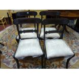 A SET OF FOUR REGENCY MAHOGANY DINING CHAIRS with carved back rails, loose pad seats and sabre front
