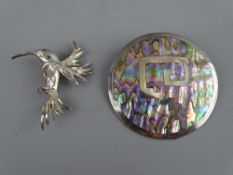 TWO SILVER BROOCHES including a humming bird with green inset eye and a 5.25 cms diameter silver and