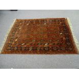 AN EASTERN STYLE TUFTED WOOL CARPET, rust ground with repeating central pattern and multi-bordered