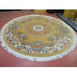 A LARGE CIRCULAR WASHED WOOLLEN CHINESE RUG, muted tones with colourful floral pattern and tasselled