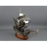 A PORTUGUESE SILVER GALLEON mounted on a wooden base, stamped to the rudder, 26 cms high, 27 cms