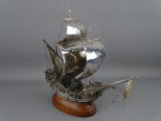 A PORTUGUESE SILVER GALLEON mounted on a wooden base, stamped to the rudder, 26 cms high, 27 cms