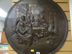A large metal circular relief wall plaque of a family scene