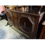 A vintage bow fronted carved decorated oak sideboard on raised feet