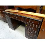 A reproduction mahogany kneehole desk with a red leather tooled top