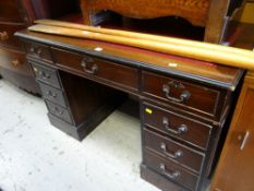 A reproduction mahogany kneehole desk with a red leather tooled top