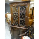 A dark oak lead glazed top Priory-style standing corner cupboard together with a similar glazed