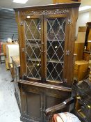 A dark oak lead glazed top Priory-style standing corner cupboard together with a similar glazed