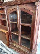 A modern hardwood two-door glazed bookcase above a single drawer base