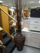 A large wicker floor vase with decorative twig contents