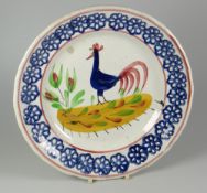 A LLANELLY POTTERY COCKEREL PLATE typically decorated with blue sponged wheel motifs to the