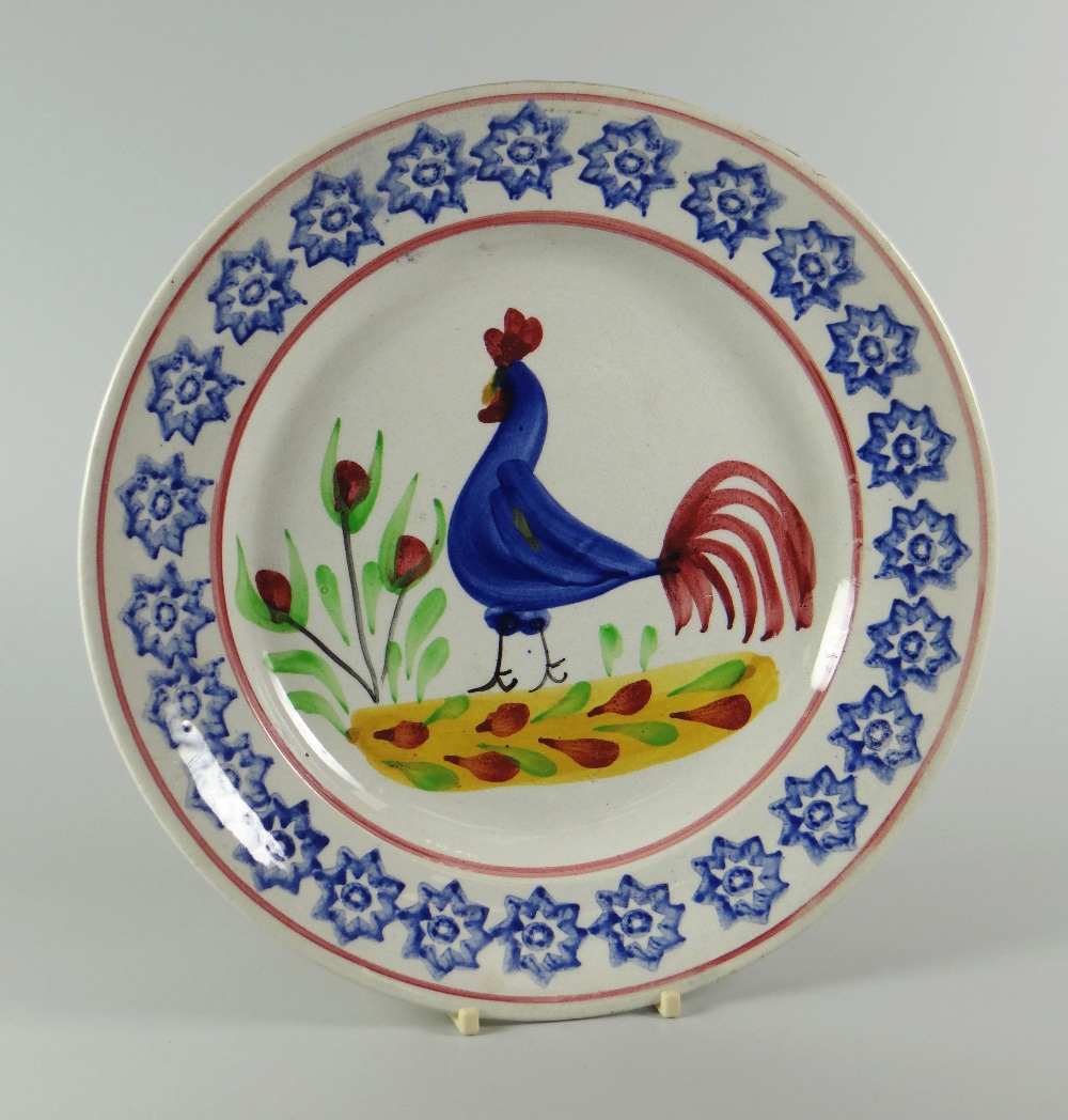 A LLANELLY COCKEREL PLATE typically decorated with blue sponged star decoration to the border, 24cms