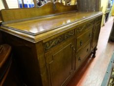 Polished wood railback sideboard with twin cupboard doors, two central drawers and carved detail