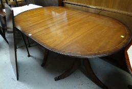 A reproduction mahogany & banded twin-pedestal extending dining table