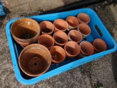 A crate of small earthenware garden flower pots (outside)