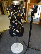 Mannequin with a parcel of costume jewellery brooches attached together with a microphone stand