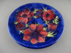A MOORCROFT 'ANEMONE' 26.5 cms DIAMETER PLATE decorated on a cobalt ground, factory marks to the