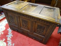 AN ANTIQUE STYLE CARVED OAK MULE CHEST with triple floral carved front panels and two lower drawers,