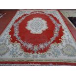 A CHINESE WASHED WOOLLEN CARPET, predominantly red ground with central floral motif and bordered
