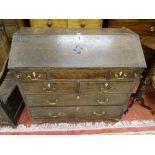 AN EARLY 19th CENTURY OAK BUREAU, the slope front revealing interior well and numerous stepped