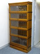 A GLOBE WERNICKE LIGHT OAK FIVE SECTION BOOKCASE with lower drawer base and shaped cap, the doors
