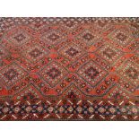 AN EASTERN STYLE CARPET, predominantly red ground with central repeating diamond pattern and