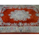 A RED GROUND CHINESE WASHED WOOLLEN CARPET with all over floral pattern and tasselled ends, 280 x