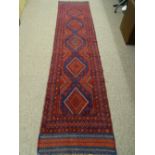 A MESHWANI CARPET RUNNER, predominantly red ground with diamond central pattern and triple