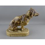 A CARVED SOAPSTONE FIGURE OF A DACHSHUND seated on an oval base, the rear inscribed 'M Neumarch', 20
