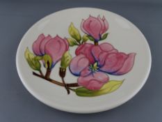 A MOORCROFT 'MAGNOLIA' 26.5 cms DIAMETER PLATE, decorated on a cream ground with factory