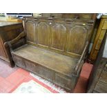 AN EARLY 19th CENTURY BOX SEAT SETTLE with shaped panel back and open arms, peg join construction on