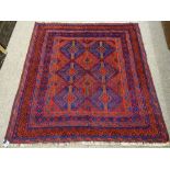 A CAZAK RUG in tonal reds and blues, multi-bordered with block diamond central pattern, 127 x 123