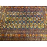 A PERSIAN STYLE RUG, predominantly blue ground in traditional style repeating patterns and tasselled