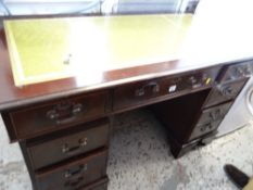 A reproduction mahogany kneehole desk with green tooled leather top
