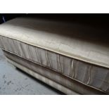 A large foot stool in a striped cream fabric
