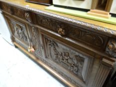 A substantial antique carved sideboard with two doors bearing carved panels of raucous tavern