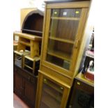 Pair of near matching light oak cabinets with single glass doors