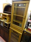 Pair of near matching light oak cabinets with single glass doors