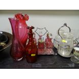 Good cut glass six bottle condiment set on a plated stand, each bottle cranberry tinted, a large