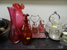 Good cut glass six bottle condiment set on a plated stand, each bottle cranberry tinted, a large