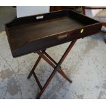 An antique butler's tray on folding stand