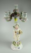 A German four-branch porcelain candelabra in the form of a young girl carrying a basket with roses