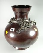 A large circular Japanese bronze vase decorated with a stylized dragon