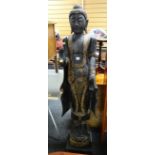 A twentieth century stained & gold painted carved Buddhist figure standing upright on a platform