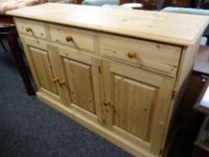 A modern pine sideboard with three cupboards & three drawers