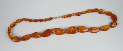 A POLISHED IRREGULAR GRADUATED AMBER BEAD NECKLACE (not tested)