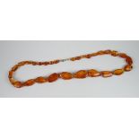 A POLISHED IRREGULAR GRADUATED AMBER BEAD NECKLACE (not tested)